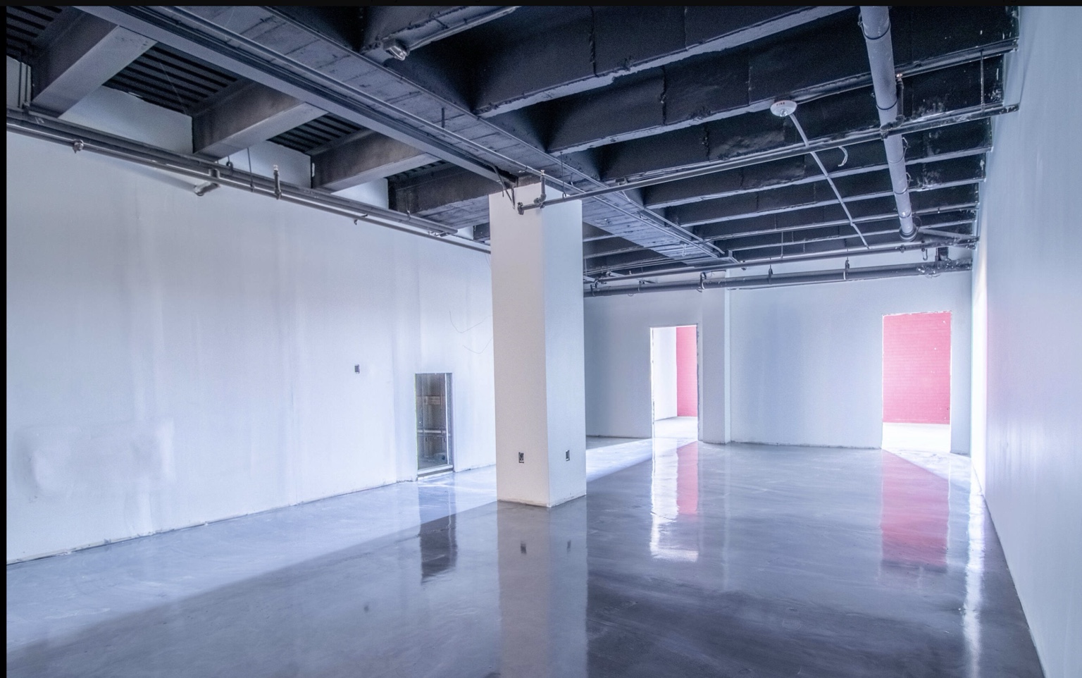 Unfinished commercial interior with exposed overhead services